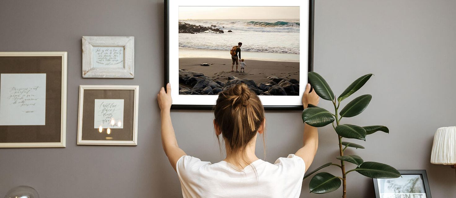 Woman hanging framed photo on wall