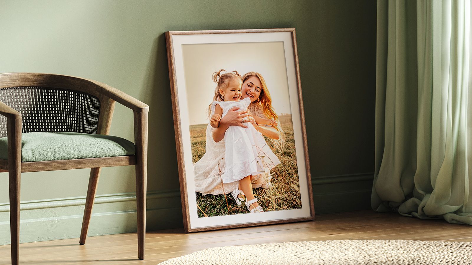 Framed photo of woman and child with natural frame and white mat leaned against a green wall next to a modern chair
