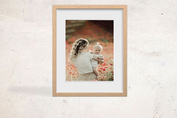 A framed print of a woman holding a baby in a flower grove