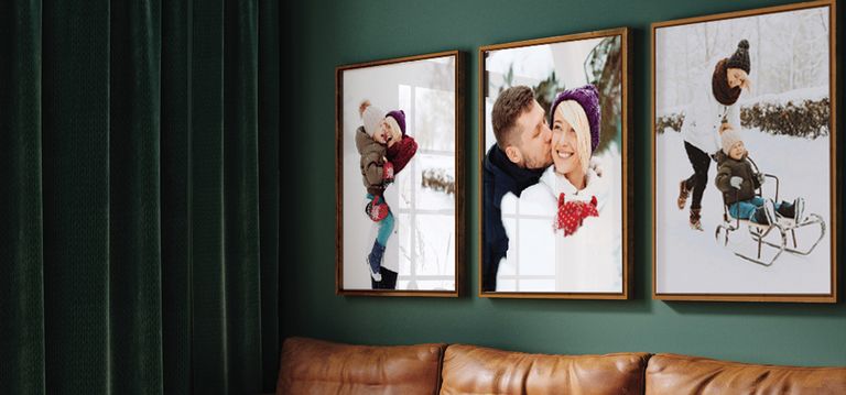 Trio of framed winter family photos above a brown couch and green wall