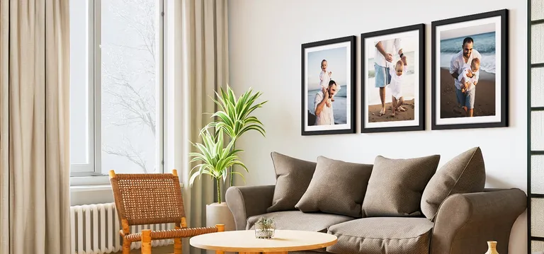 Framed father and child photos in black frames with white mats in a above a brown sofa