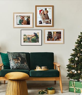 Holiday framed photos on a light colored wall near a Christmas Tree and Green furniture. 