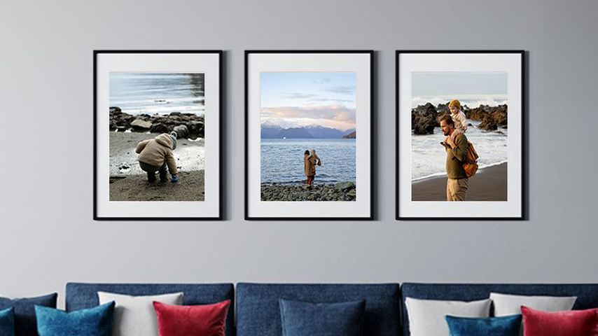 Trio of 2 framed photos of a family by the water in black frames with white mats