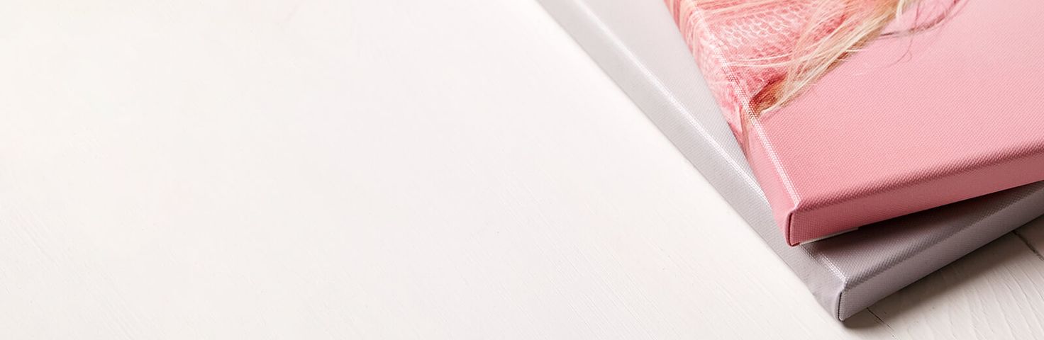 Close-up of two stacked photo canvas prints on a light wooden surface.