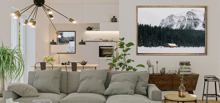 Framed photo of cabin in the snow against a neutral living area with gray couch and plants