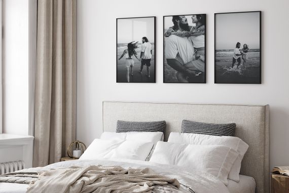 Black and white framed photos with White mats in Black Frames above a light gray couch with winter throw pillows