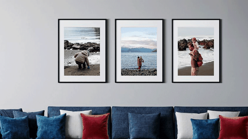 3 framed phots above a blue sofa with red, white and blue accent pillows