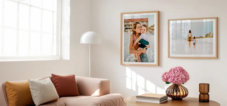 Framed mother and child photos in gold frames with white mats in a spring decorated room with a pink flower arrangement and neutral colored furniture 