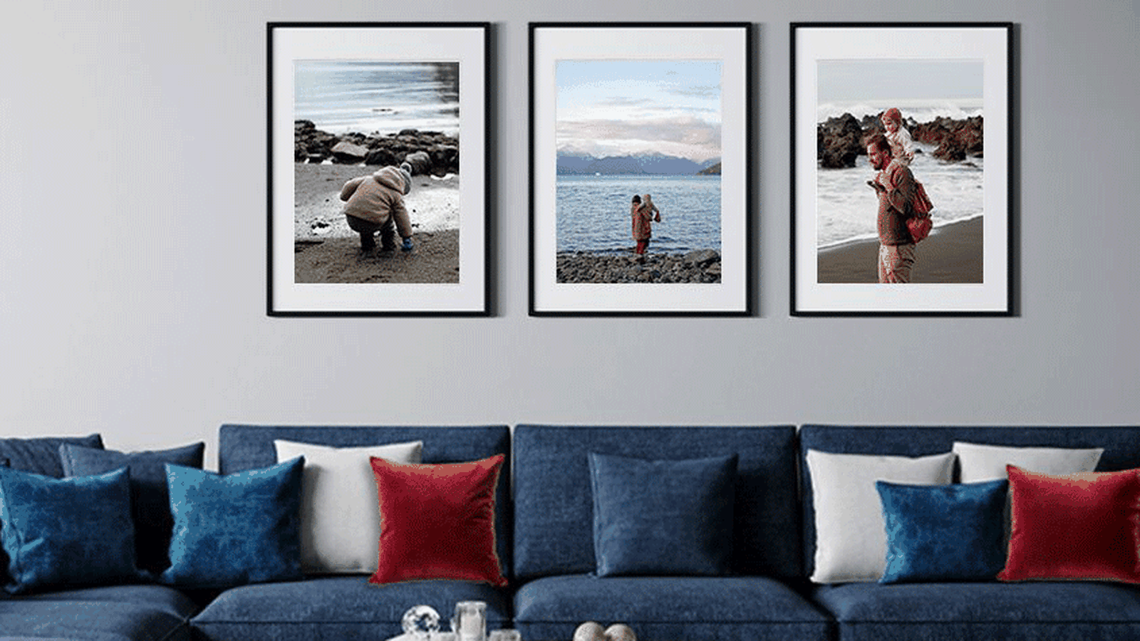 3 framed phots above a blue sofa with red, white and blue accent pillows