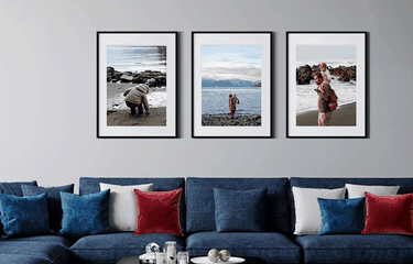 3 framed phots above a blue sofa with red, white and blue accent pillows
