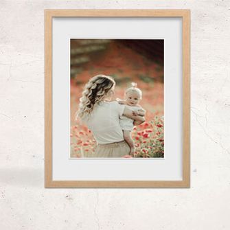 A framed print of a woman holding a baby in a flower grove
