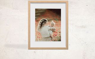 A framed print of a woman holding a baby in a flower grove