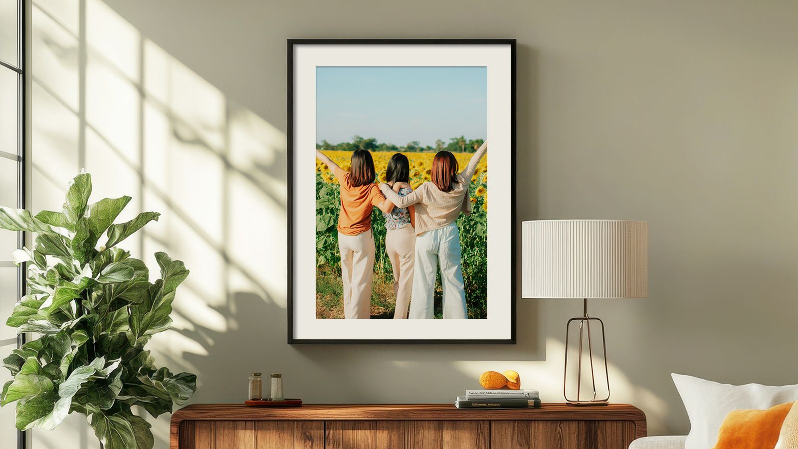 Frame photo in black frame with white mat with 3 women embracing in a filed in a brightly lit room