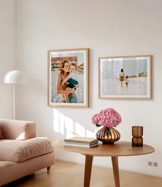 Framed mother and child photos in gold frames with white mats in a spring decorated room with a pink flower arrangement and neutral colored furniture 