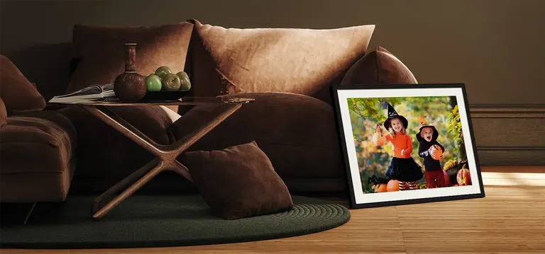 Framed photo of children dressed for Halloween in black frame with white mat next to a tan sofa