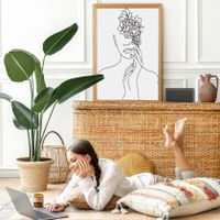 A person lying on the floor using their laptop in front of a large art print