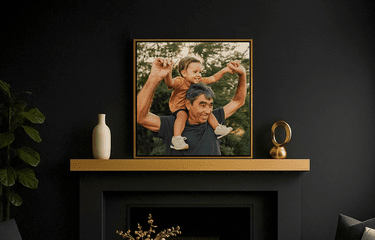 Framed photo of grandfather with grandchild on his shoulders in a dark room with gold accents and plants