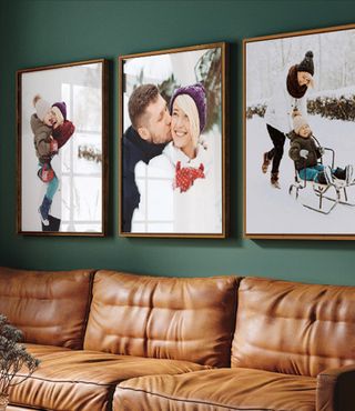 Trio of framed winter family photos above a brown couch and green wall